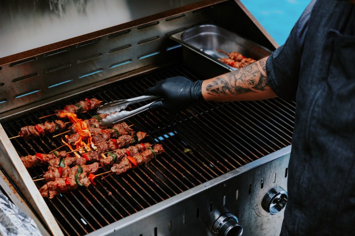 a person cooking hot dogs on a grill