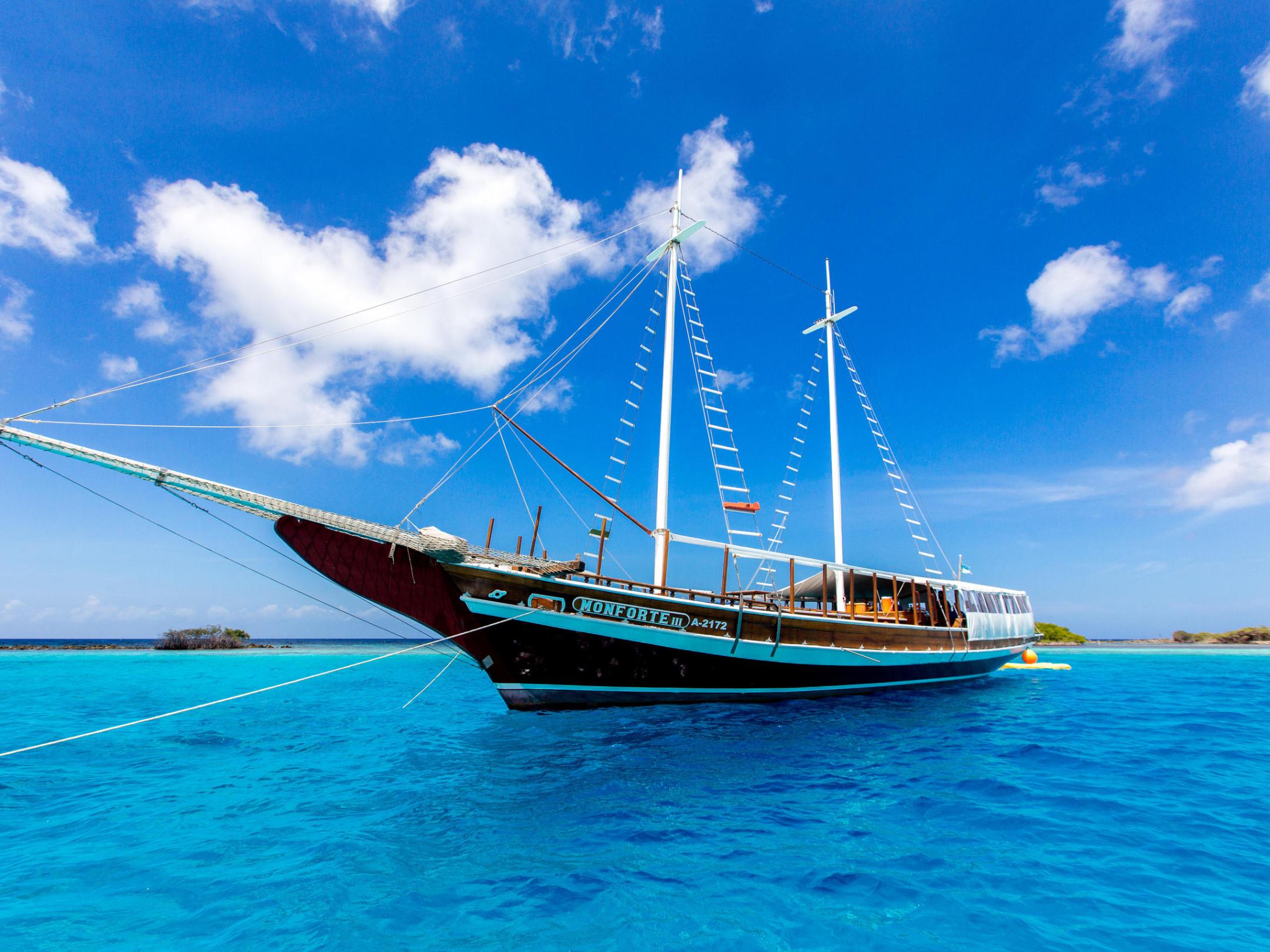 a blue and white boat sitting next to a body of water