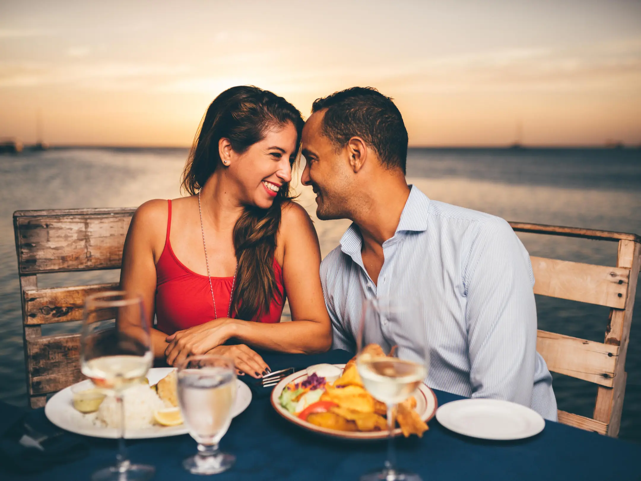 a man and a woman sitting at a table in front of water