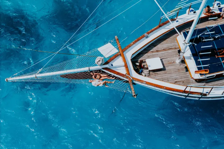People relaxing on a yacht's bow over clear blue water.