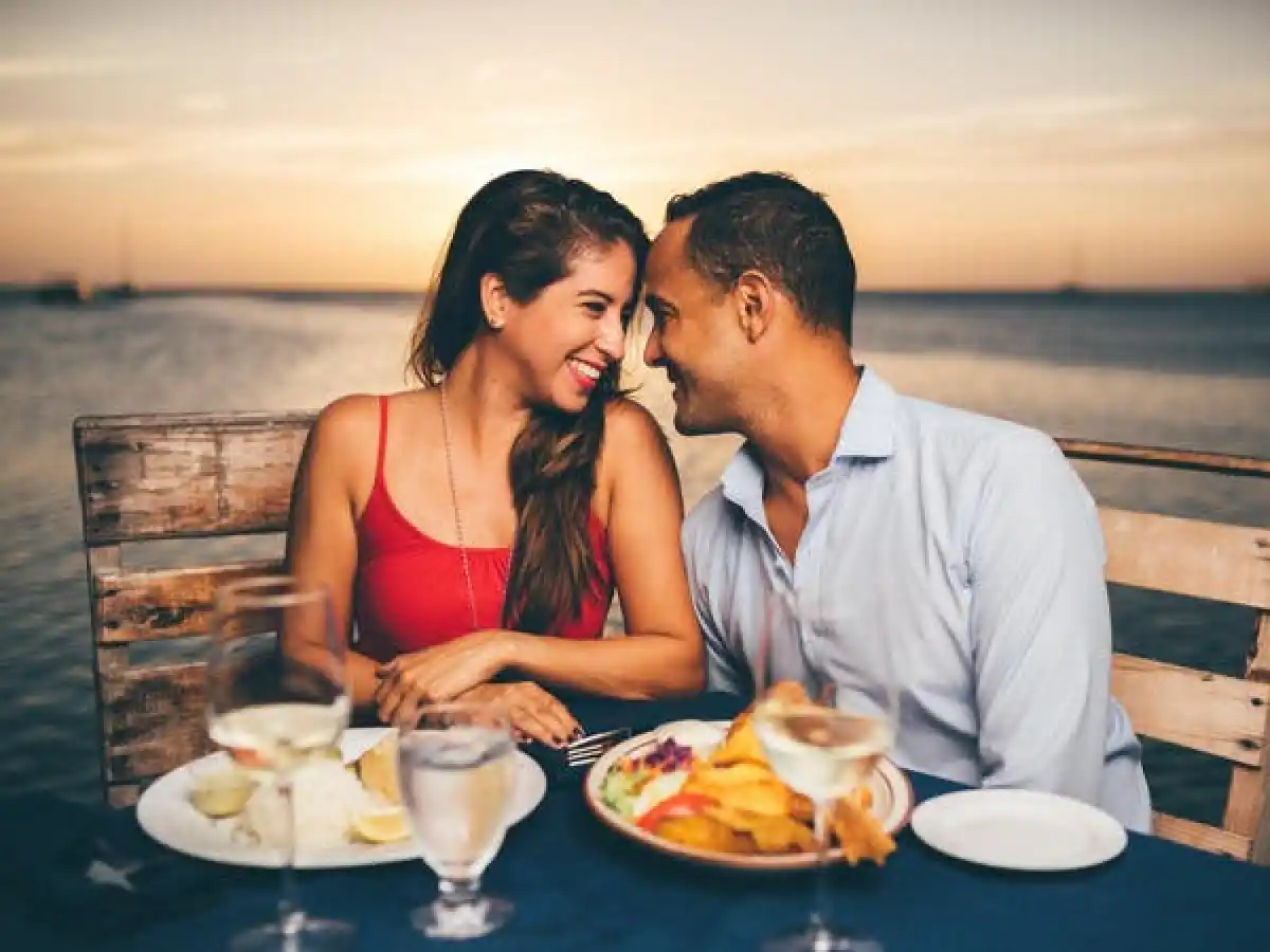 a man and a woman sitting at a table with food and water