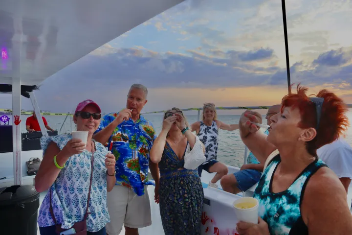 Group of people enjoying drinks on a boat during sunset.