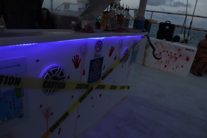 Bar with spooky decor, caution tape, red handprints, and blue lighting.