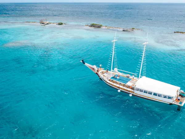 Sailboat anchored in clear turquoise sea near a small island.
